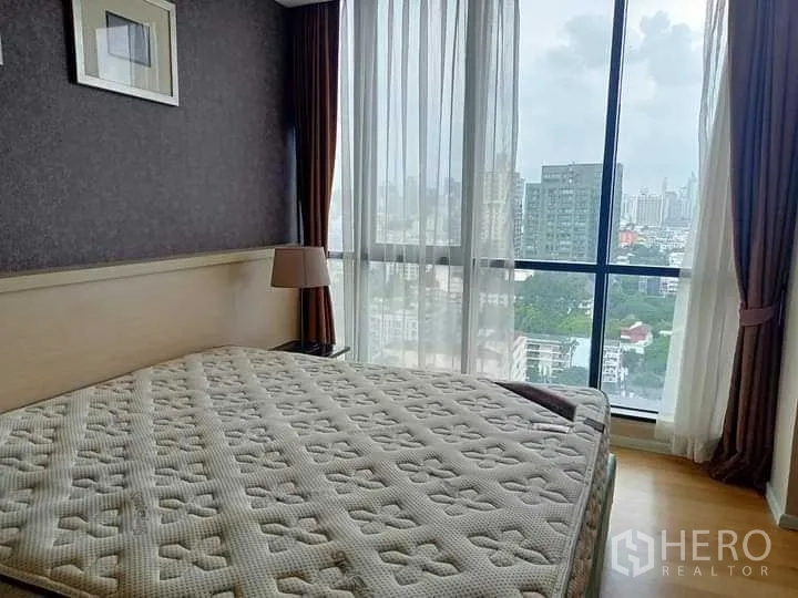 公寓 出租在Watthana, Bangkok - 卧室带壁挂层架与电视，木地板，拥有城市景观大窗。