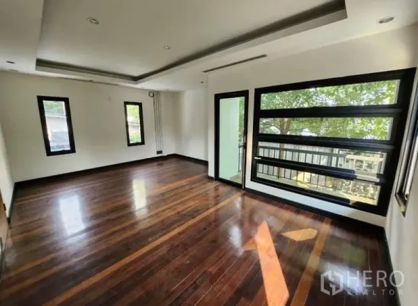 Home Office for rent in Lat Phrao, Bangkok - Bright home-office room with dark hardwood floors, recessed ceiling and large black-framed windows overlooking greenery.