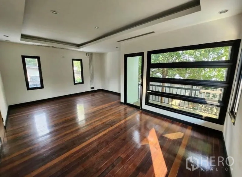 Home Office for rent in Lat Phrao, Bangkok - Bright home-office room with dark hardwood floors, recessed ceiling and large black-framed windows overlooking greenery.