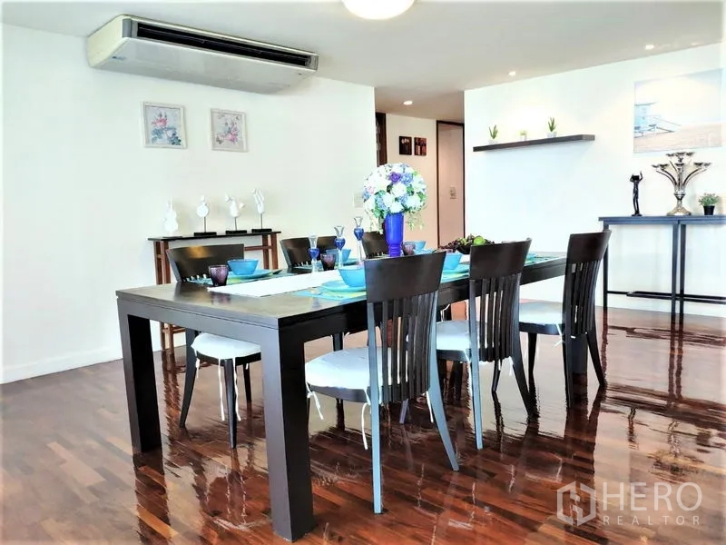 Condominium for rent in Bang Rak, Bangkok - Spacious dining room with a six-seat dark wood table, air conditioning and glossy timber flooring.