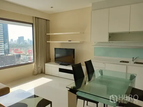 公寓 出租在Sathon, Bangkok - 采光充足的客餐厅，落地观景窗、白色厨房、电视柜与玻璃餐桌，沙吞公寓内景。