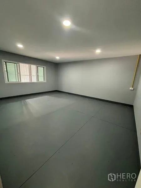 Warehouse for rent in Mueang Pathum Thani, Pathum Thani - Bright office room inside the warehouse with windows and recessed ceiling lights over a grey floor.