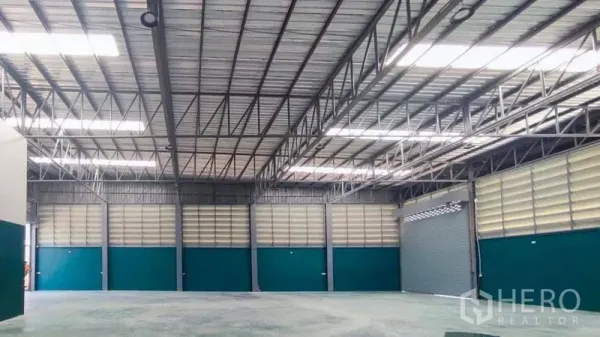 Factory for sale in Bang Pakong, Chachoengsao - High-ceiling warehouse hall with steel trusses, skylights and roller doors