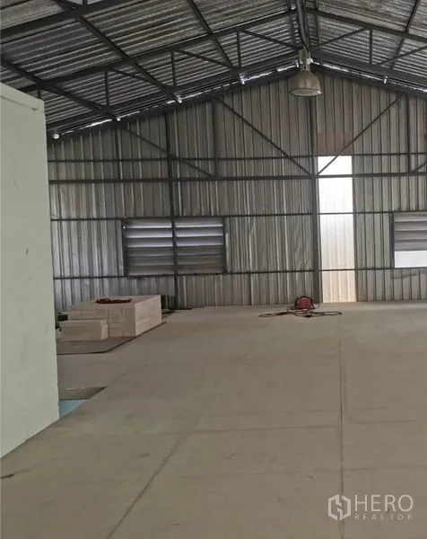 Warehouse for rent in Prawet, Bangkok - Metal-clad warehouse hall with gable roof, louvered windows, and clear open work area.
