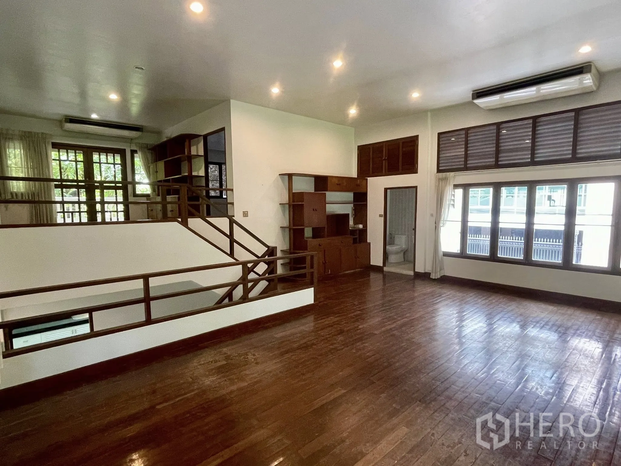 Detached House for rent in Pathum Wan, Bangkok - Large open living room with air-conditioning, built-in shelving, and bathroom access.