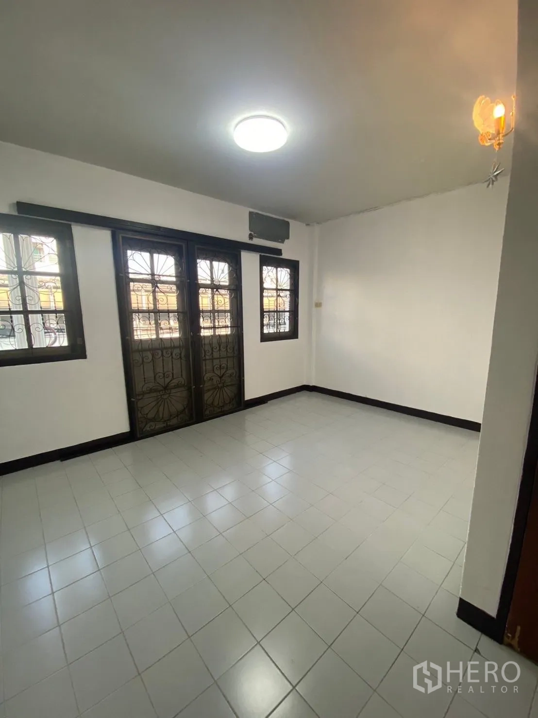 Townhouse for rent in Huai Khwang, Bangkok - Third bedroom with balcony access and neutral floor tiles, ready to furnish.