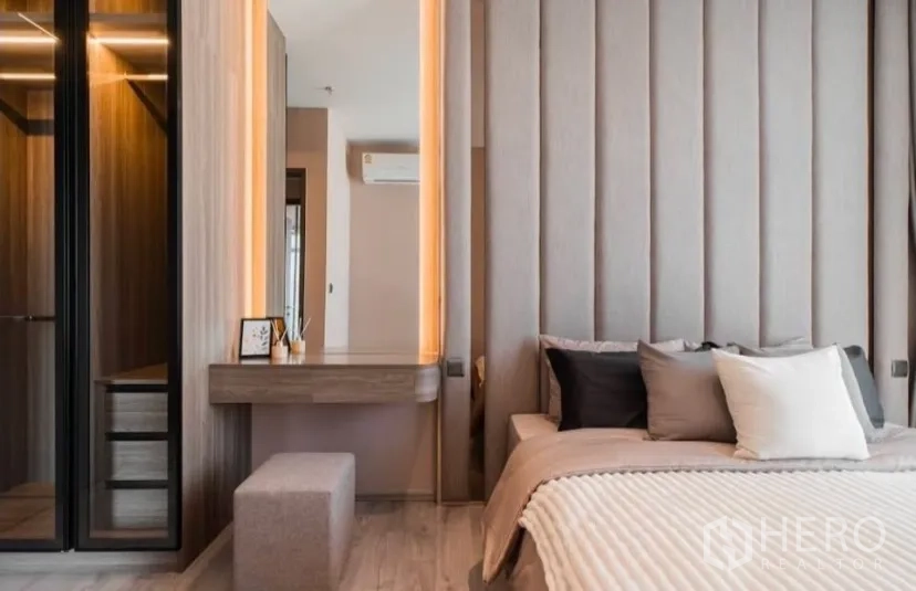 Condominium for rent in Watthana, Bangkok - Bedroom with dressing table and glass-door wardrobe with warm lighting.