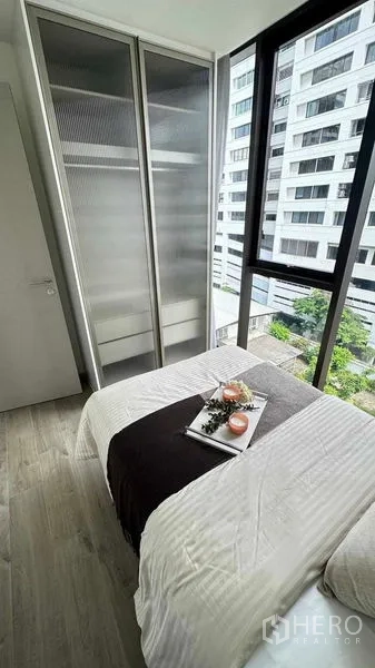 คอนโด ให้เช่าในWatthana, Bangkok - ห้องนอนขนาดกะทัดรัดพร้อมหน้าต่างบานใหญ่ ชุดเครื่องนอนสีขาว และตู้เสื้อผ้าบานเลื่อนกระจกฝ้า วิวเมือง