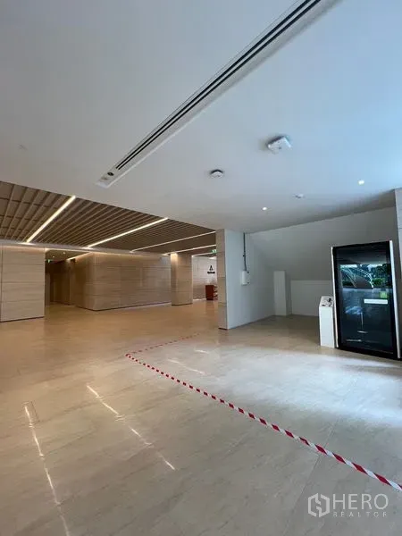 Retail Space for rent - Modern lobby with light stone floors and slatted ceiling showing a compact retail bay.