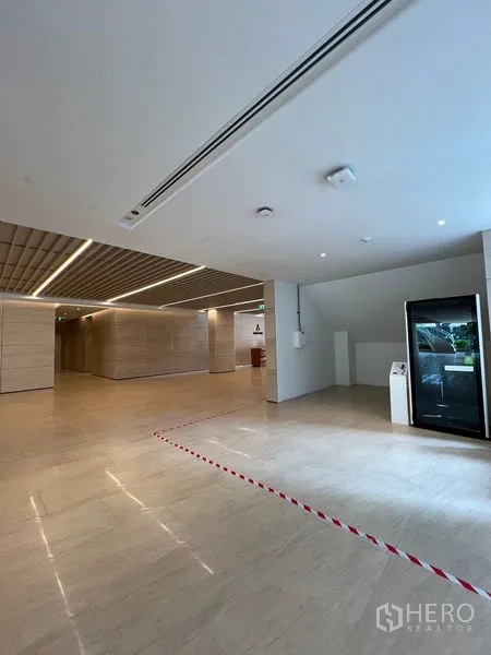 Retail Space for rent - Modern lobby with light stone floors and slatted ceiling showing a compact retail bay.