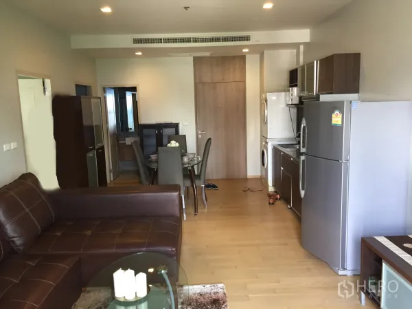 公寓 出租在Watthana, Bangkok - 开放式客餐厅，皮沙发、木地板，配备家电的一体化厨房。