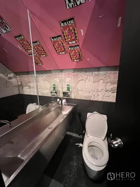Retail Space for rent in Watthana, Bangkok - Restroom with stainless trough sink, toilet, and pink ceiling detail.