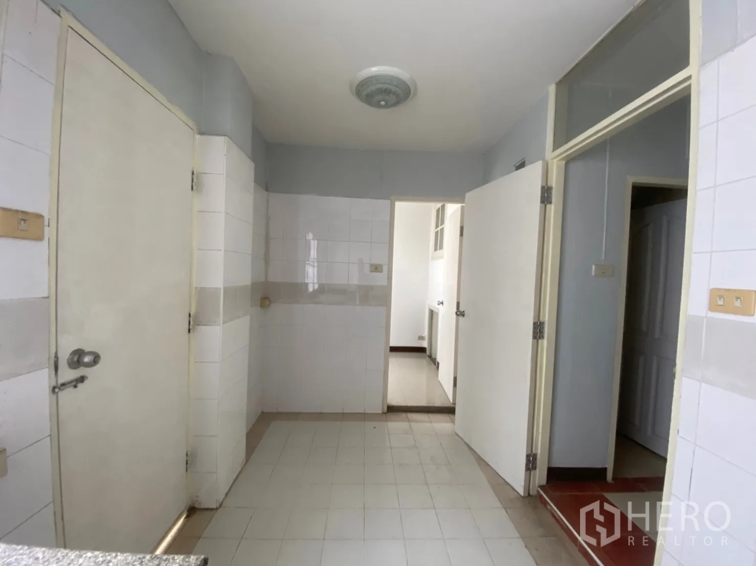 Townhouse for rent in Watthana, Bangkok - Simple tiled kitchen with multiple doors and utility area.