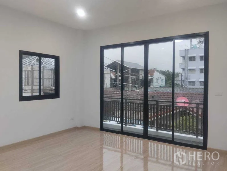 Detached House for sale in Phra Khanong, Bangkok - Upper room with sliding glass doors opening to a balcony and neighborhood view.