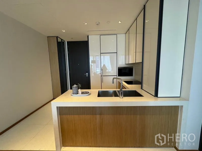 Condominium for rent - Modern kitchen with white cabinetry, island sink, and integrated appliances.