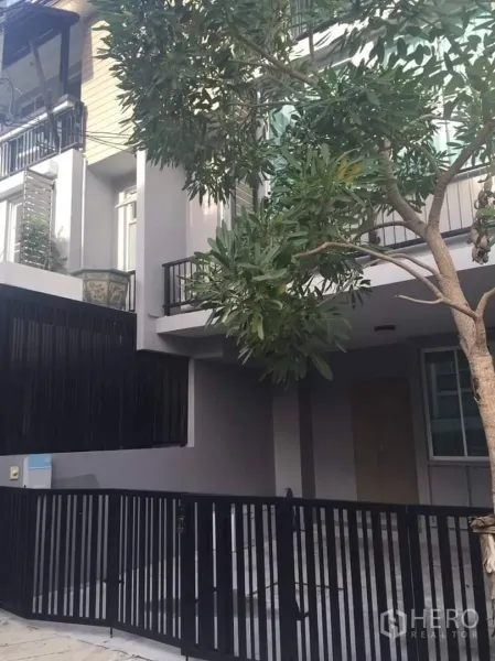 Townhouse for rent or sale in Lat Phrao, Bangkok - Modern three‑storey townhouse exterior with balconies and a black metal gate.