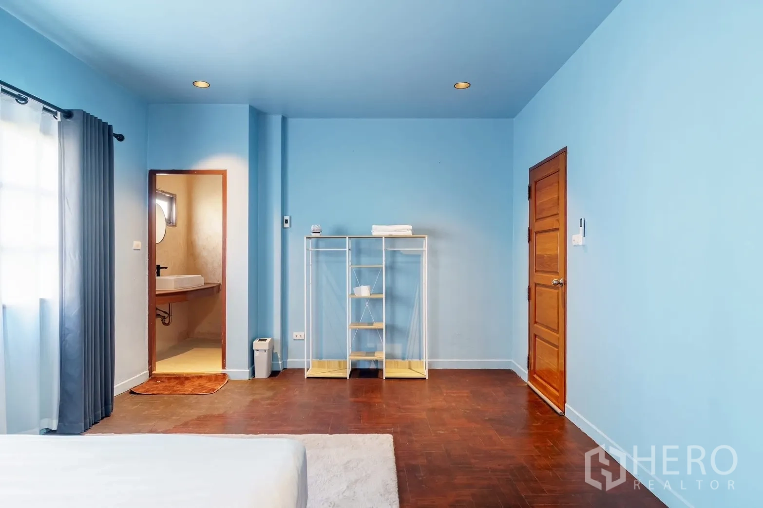 ทาวน์เฮาส์ for rent in Watthana, Bangkok - ห้องนอนโทนสีฟ้าพร้อมประตูห้องน้ำในตัวและชั้นวางแบบเปิด พื้นไม้