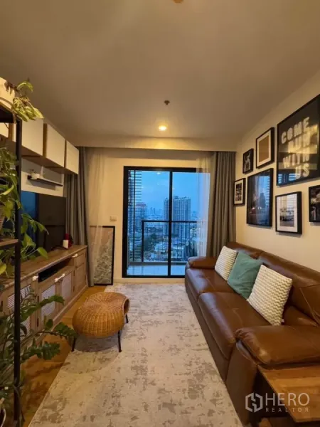 คอนโด ให้เช่าในWatthana, Bangkok - ห้องนั่งเล่นสว่าง พรมผืนใหญ่ ตั่งหวาย และระเบียงมองเห็นวิวกรุงเทพฯ