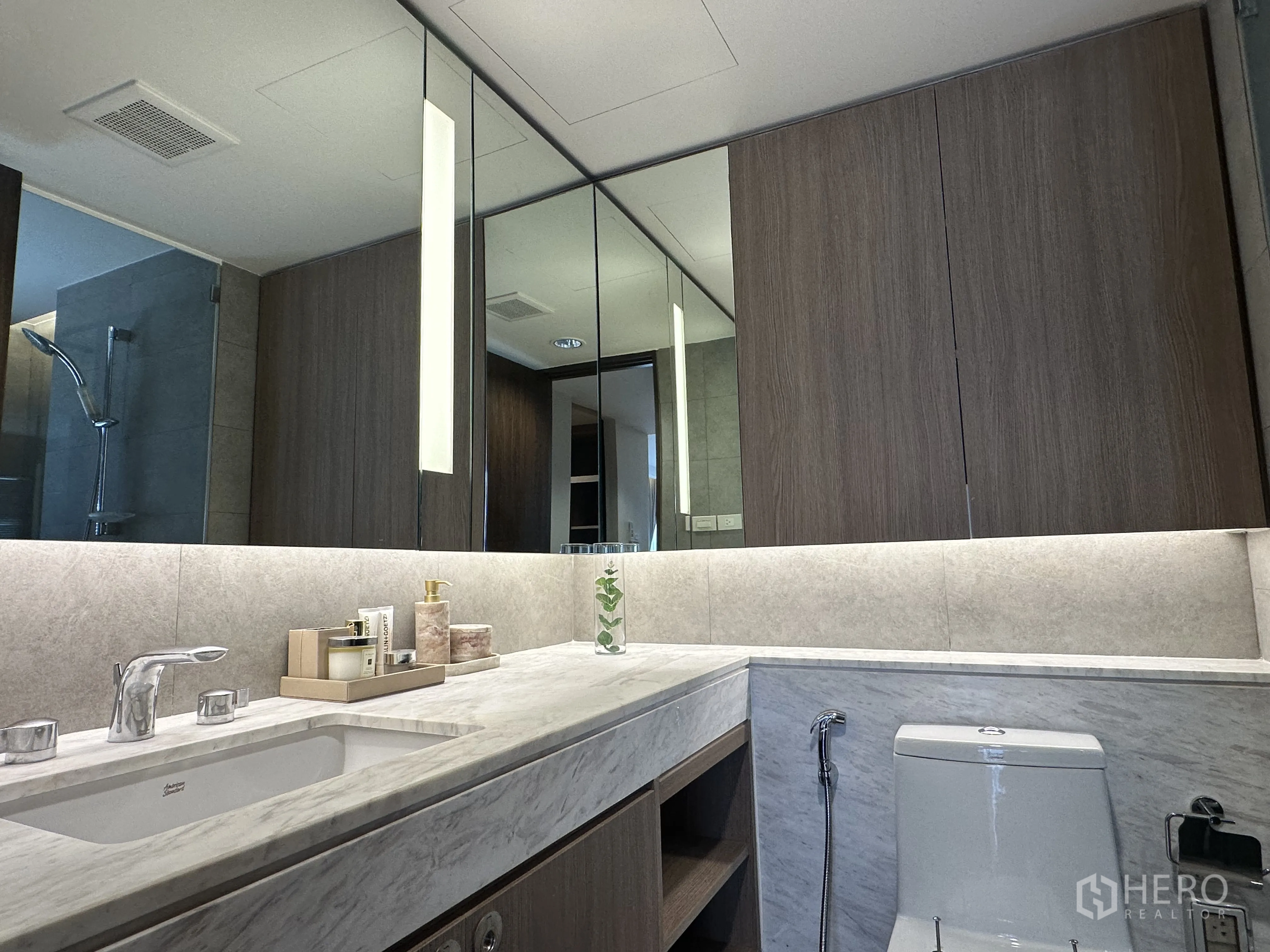 Condominium for rent in Khlong Toei, Bangkok - Modern bathroom with extended vanity, storage cabinets and shower.
