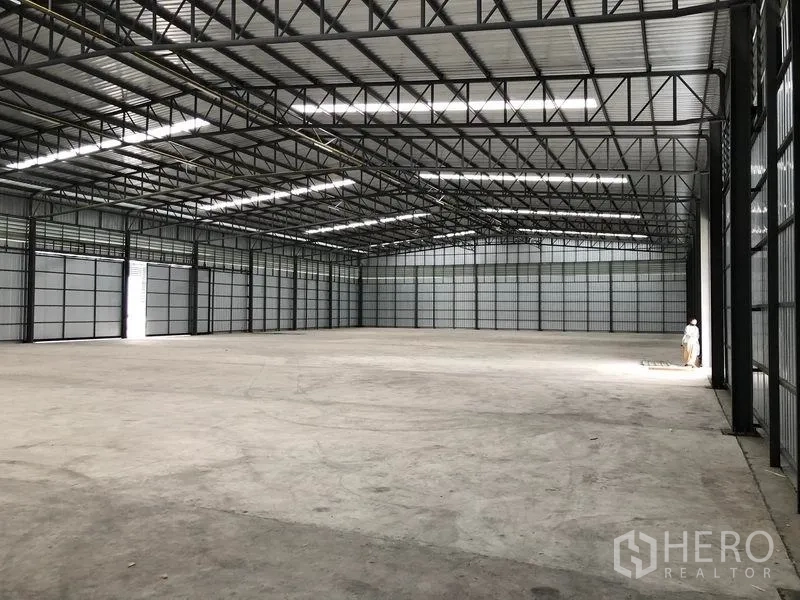 货栈 出租在Pathum Thani - 开阔的仓库内部，天窗与大门带来明亮采光与便捷通行。