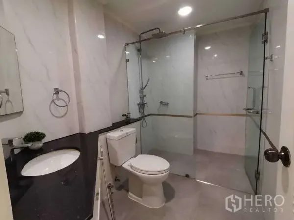 房间 出租 - 现代浴室，玻璃淋浴间、雨淋花洒与大理石纹墙面。