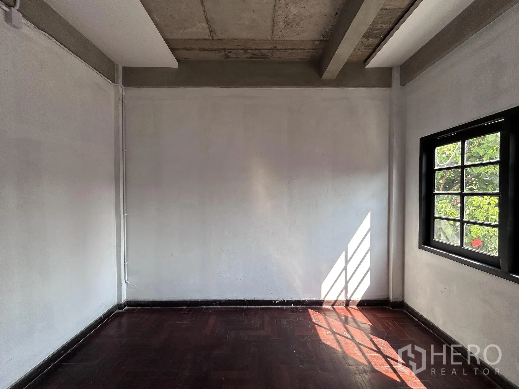 家庭办公室 for rent or sale in Watthana, Bangkok - 温馨小房，深色木地板，窗外可见绿植。