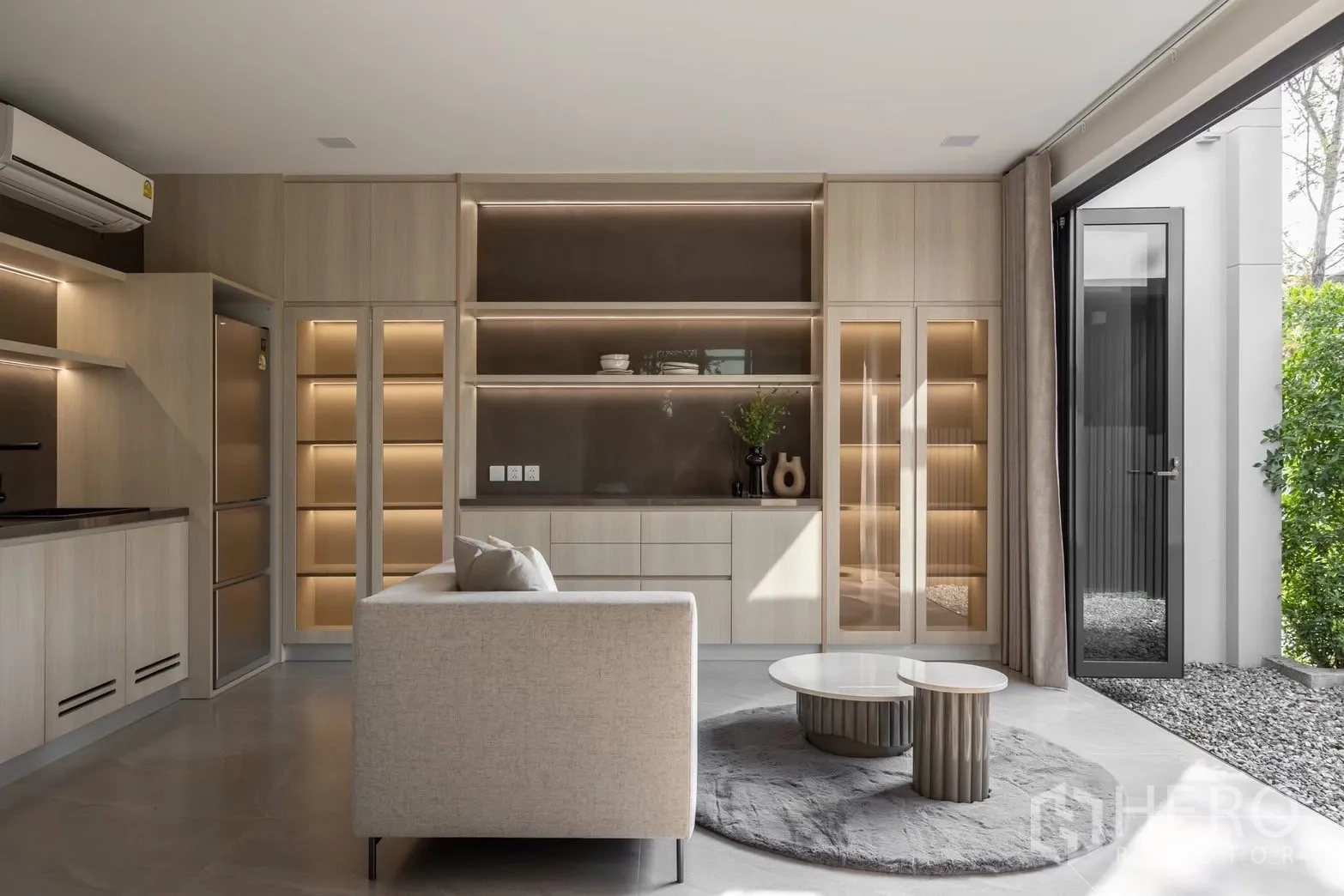 Detached House for rent in Saphan Sung, Bangkok - Lounge opening to the garden via sliding doors, built-in shelving, and round coffee tables.