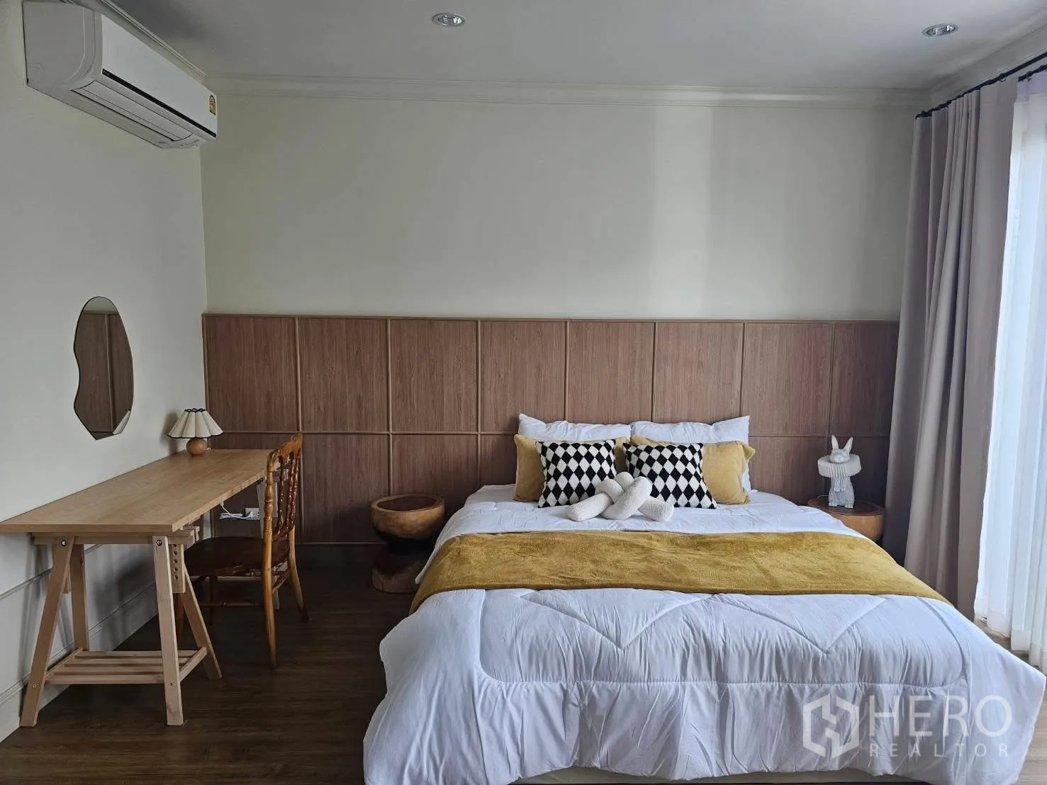 Townhouse for rent in Saphan Sung, Bangkok - Primary bedroom with wood headboard, desk, air-conditioning, and a large window with drapes.