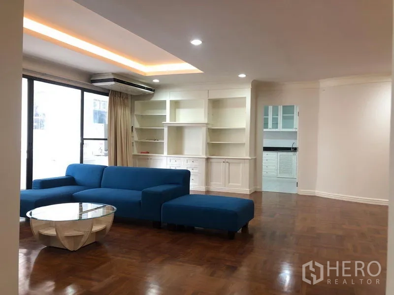 คอนโด ให้เช่าในWatthana, Bangkok - ห้องนั่งเล่นกว้าง โซฟาสีน้ำเงิน ชั้นบิลท์อิน พื้นปาร์เกต์ และประตูบานเลื่อนรับแสง