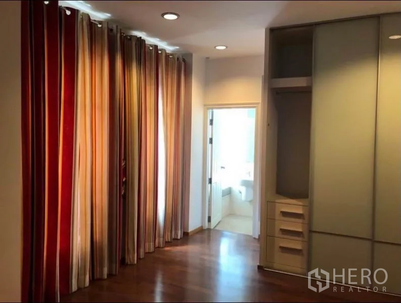 Townhouse for rent in Chatuchak, Bangkok - Bedroom corridor with floor-to-ceiling striped curtains, built-in wardrobe and an ensuite door.