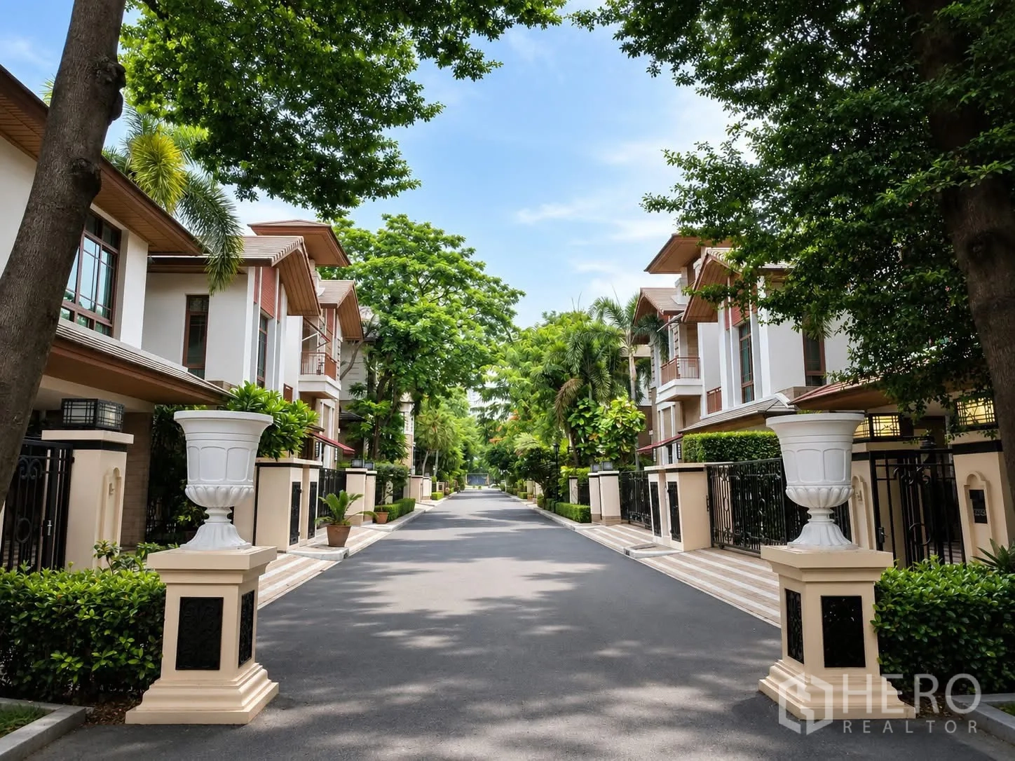 独栋房屋 for rent in Watthana, Bangkok - 带装饰柱的社区道路，两侧为别墅排屋。