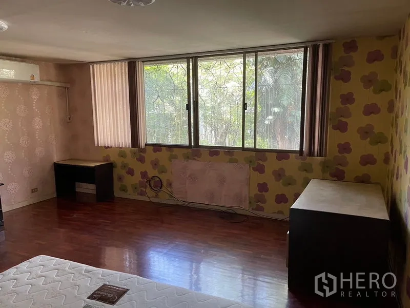 Home Office for rent in Watthana, Bangkok - Bedroom with wide windows and decorative grilles bringing natural light to wood floors.