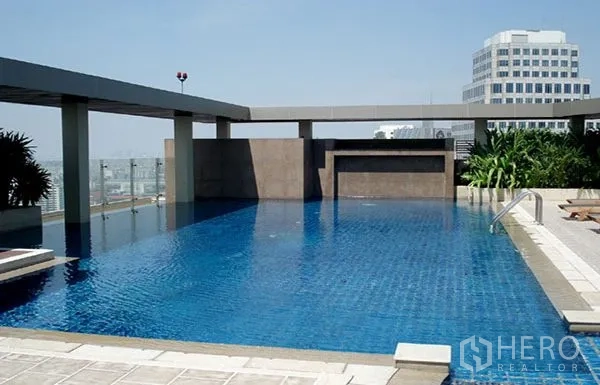 Condominium for rent in Khlong Toei, Bangkok - Rooftop swimming pool with city skyline views and sun deck seating.