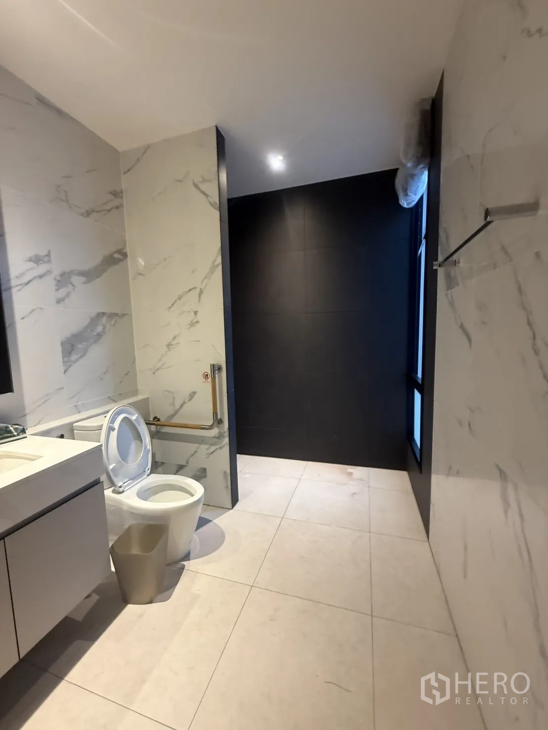 Detached House for rent in Saphan Sung, Bangkok - Modern bathroom with marble walls and a dark-tiled shower zone.