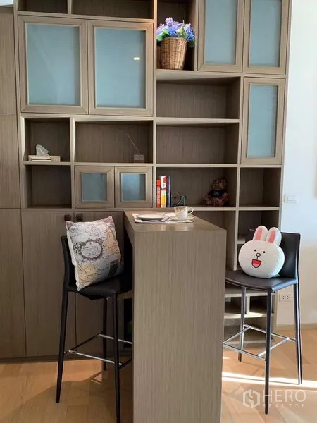 Condominium for rent in Phaya Thai, Bangkok - Tall breakfast bar with two stools set against custom floor-to-ceiling storage shelves.