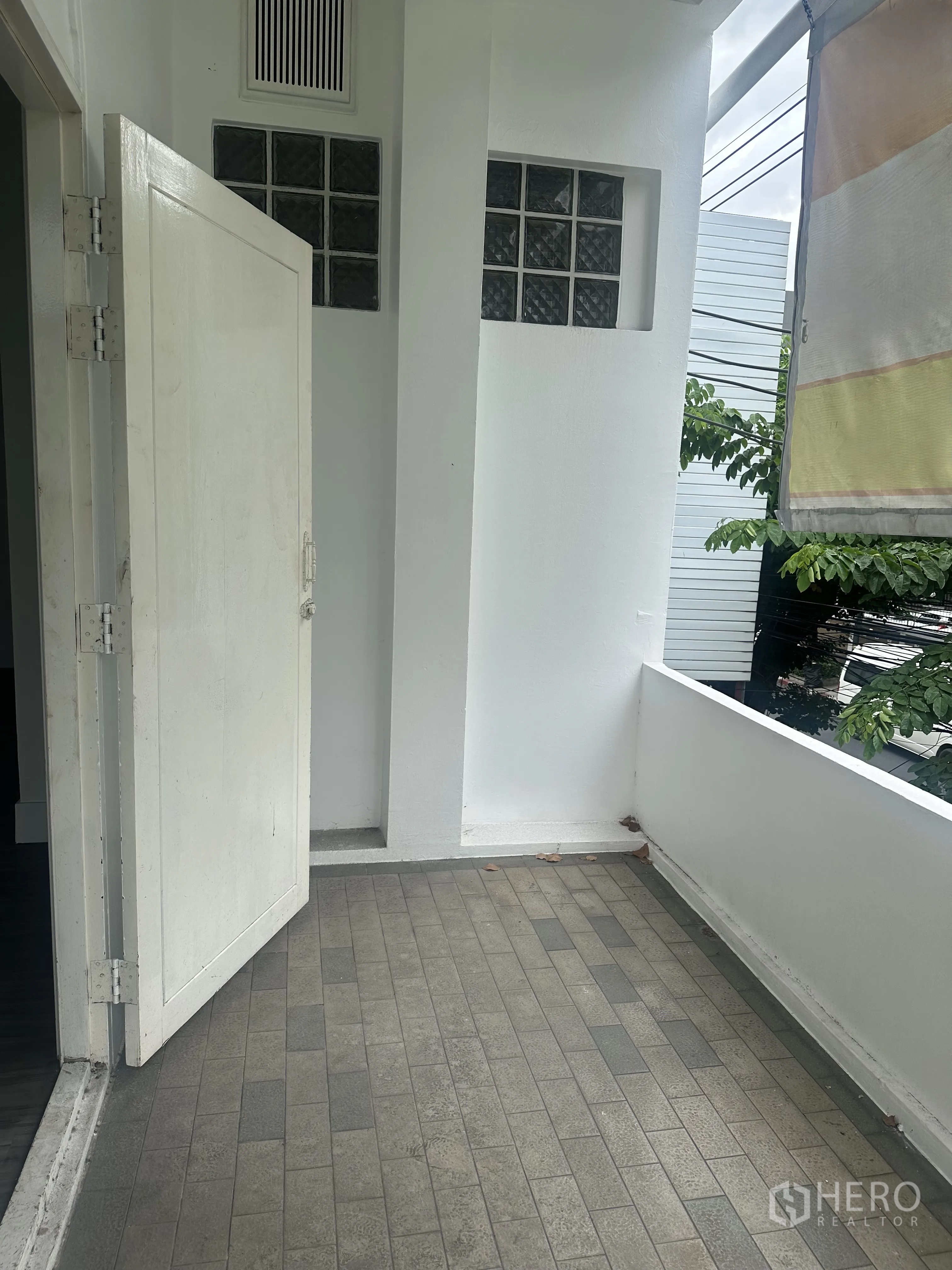 Retail Space for rent in Bang Rak, Bangkok - Small covered balcony with tiled floor and open white door.