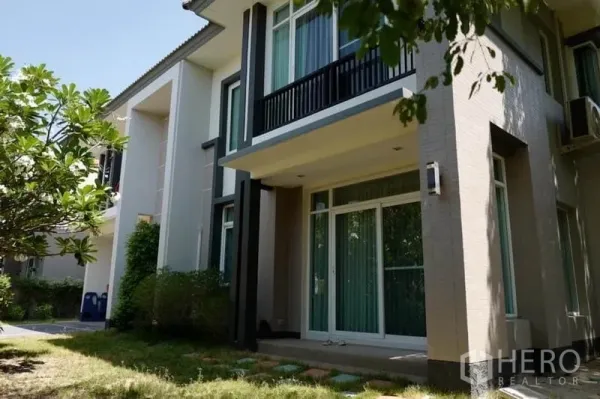 独立式住宅 出售在Pak Kret, Nonthaburi - 房屋后侧外立面，设阳台、推拉门与草坪花园。