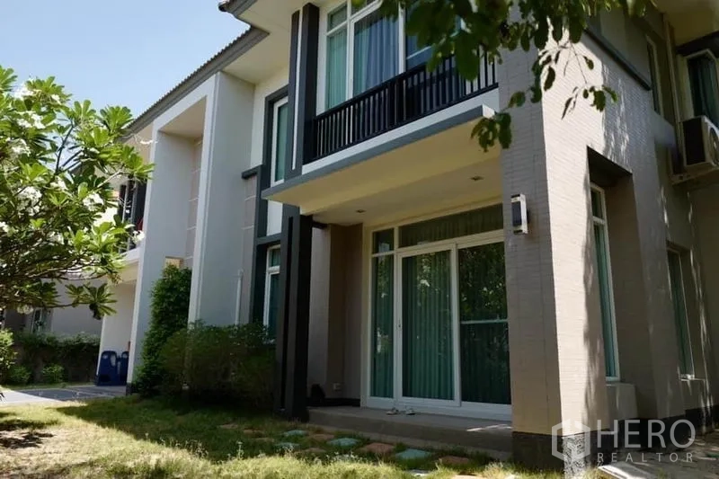 独立式住宅 出售在Pak Kret, Nonthaburi - 房屋后侧外立面，设阳台、推拉门与草坪花园。