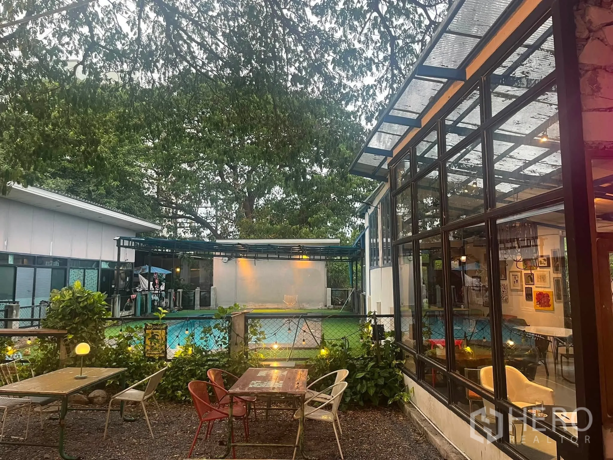 Retail Space for rent in Watthana, Bangkok - Garden patio beside the glass façade with outdoor seating and a view of a pool beyond the fence.