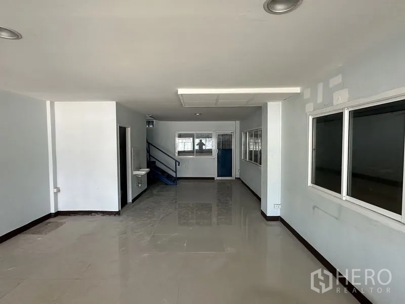 Warehouse for rent in Bueng Kum, Bangkok - Ground-floor office area with tiled floor, multiple windows and doorway to stairs.