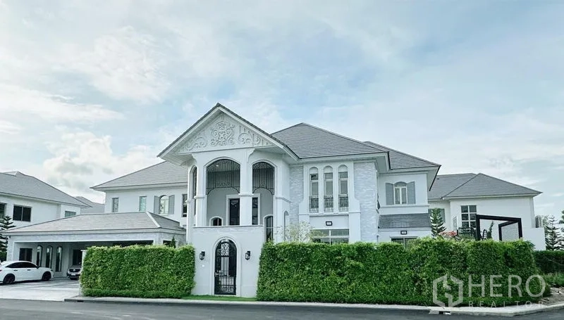 独立式住宅 出租在Lat Krabang, Bangkok - 正立面外观，修剪整齐的绿篱前的豪华独栋别墅。