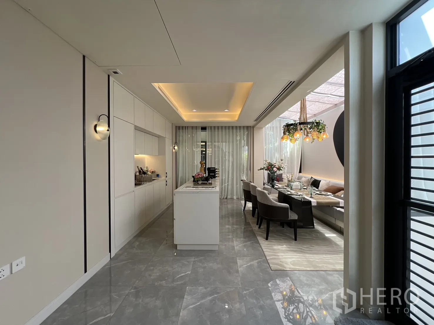 Semi-detached House for sale in Yan Nawa, Bangkok - Open-plan white kitchen with island beside a bright dining area and floor-to-ceiling windows.