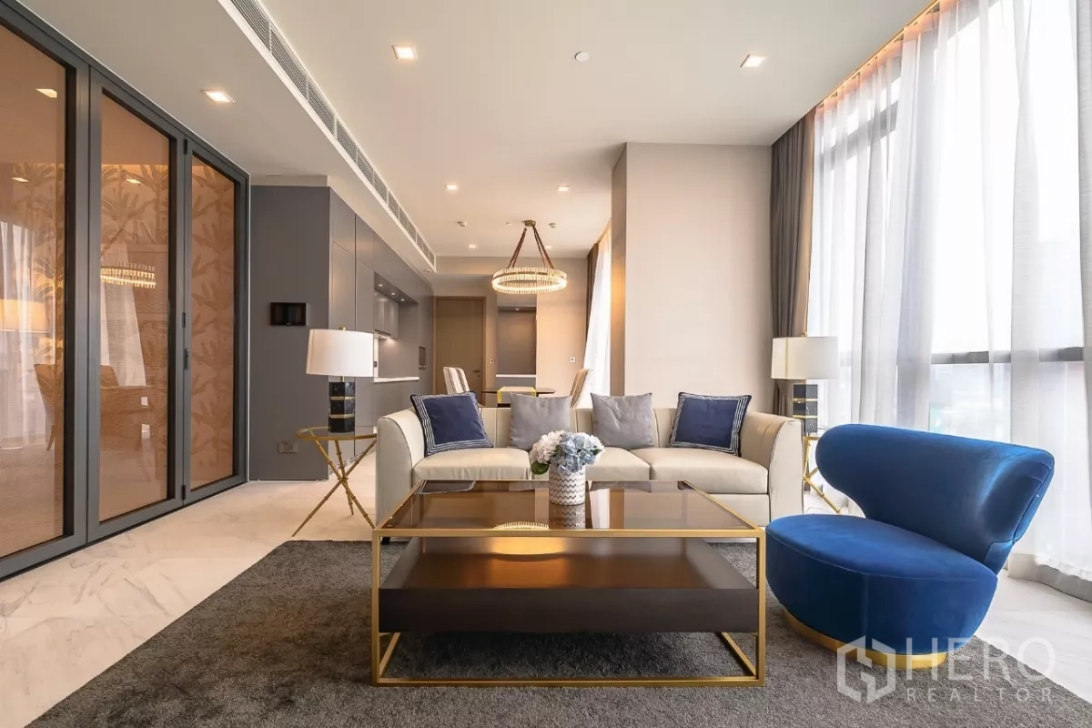 คอนโด ให้เช่าในWatthana, Bangkok - ห้องนั่งเล่นร่วมสมัย โซฟาสีครีม เก้าอี้สีน้ำเงิน โต๊ะกลางกระจก และครัวแพนทรี