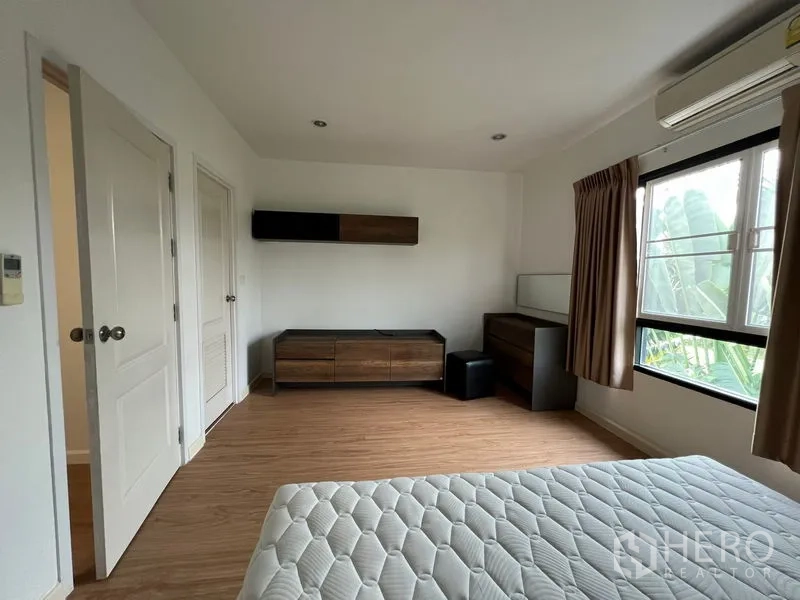Townhouse for rent in Bang Kapi, Bangkok - Spacious bedroom with built-in low cabinets and window bringing greenery views.