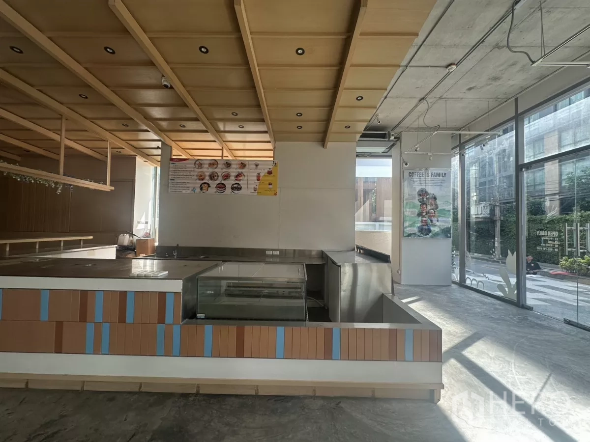 Retail Space for rent - Corner service bar with refrigerated display case, wood panels, and street-facing windows bringing in daylight.