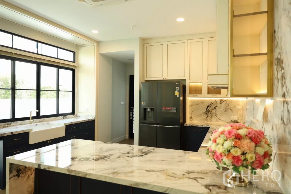 Detached House for rent or sale in Saphan Sung, Bangkok - Gourmet kitchen with marble island, backsplash, custom cabinetry, and modern refrigerator.