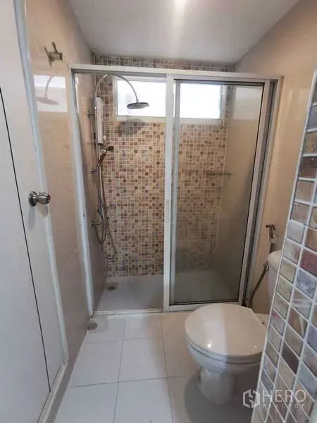 Townhouse for rent in Chatuchak, Bangkok - Compact bathroom with glass-enclosed shower and mosaic tile walls.