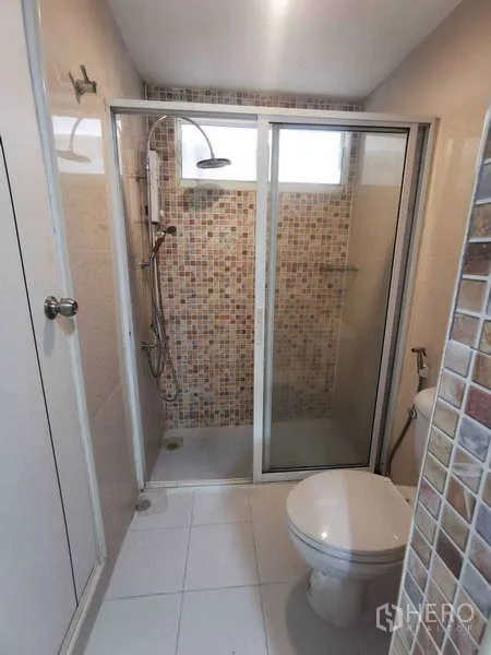 Townhouse for rent in Chatuchak, Bangkok - Compact bathroom with glass-enclosed shower and mosaic tile walls.