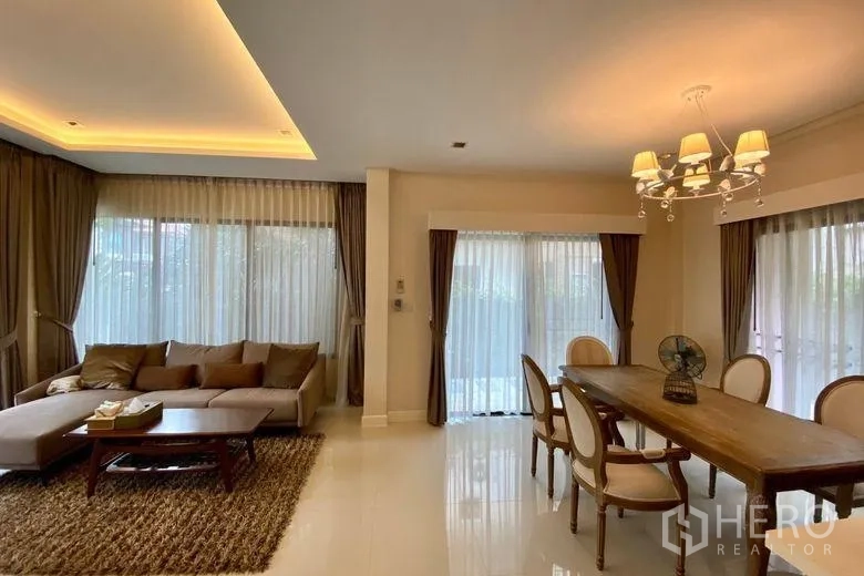 Detached House for rent in Sai Mai, Bangkok - Bright open-plan living and dining area with cove lighting, sofa set and large windows.