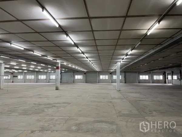 Factory for rent in Phra Samut Chedi, Samut Prakan - Large indoor industrial hall with long rows of lights, pillars and wide unobstructed space.